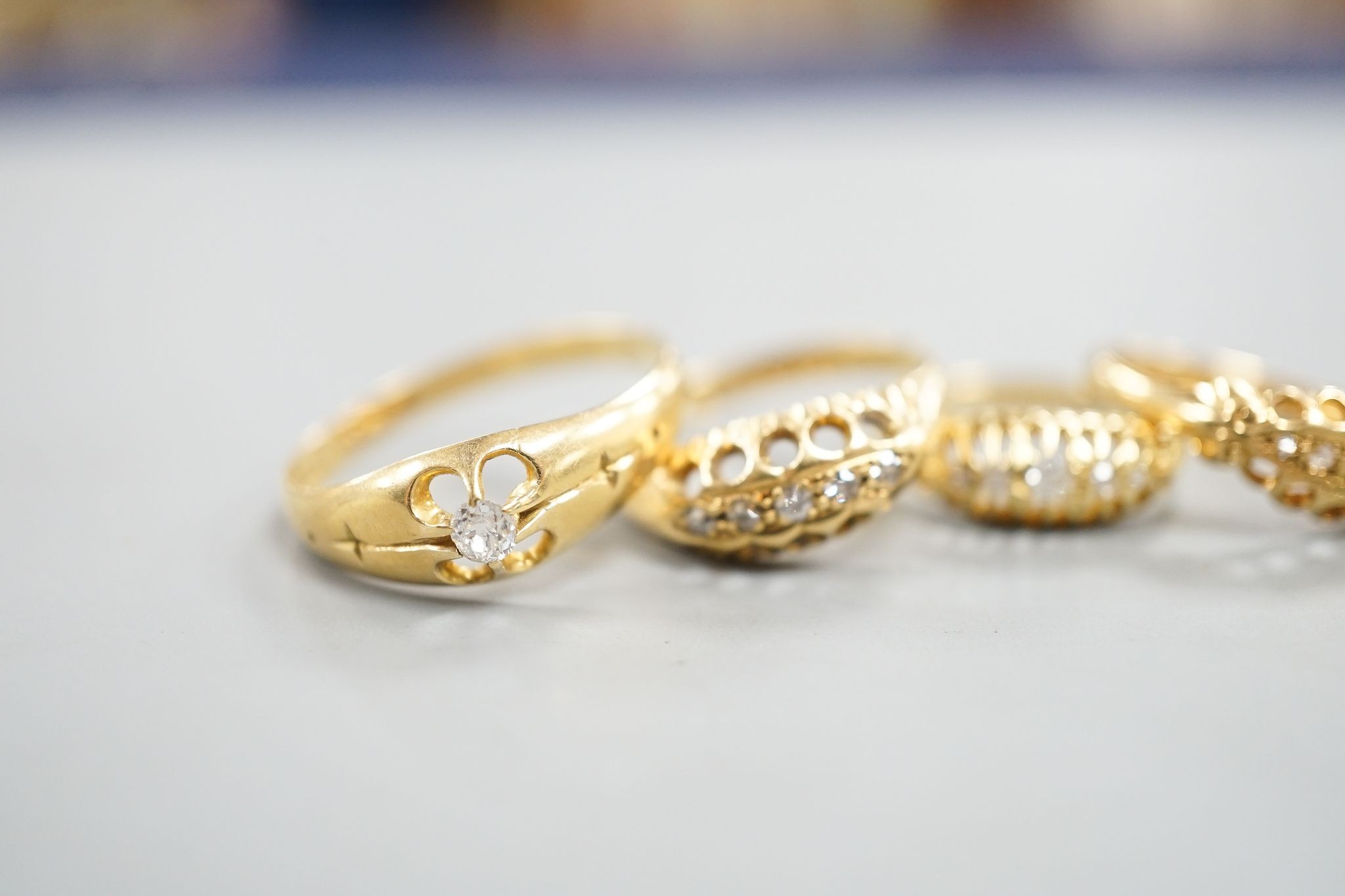 Three early 20th century 18ct gold and five stone diamond chip set rings, an 18ct , sapphire and diamond chip set ring and a late Victorian 18ct gold and solitaire diamond ring, gross weight 12.1 grams.